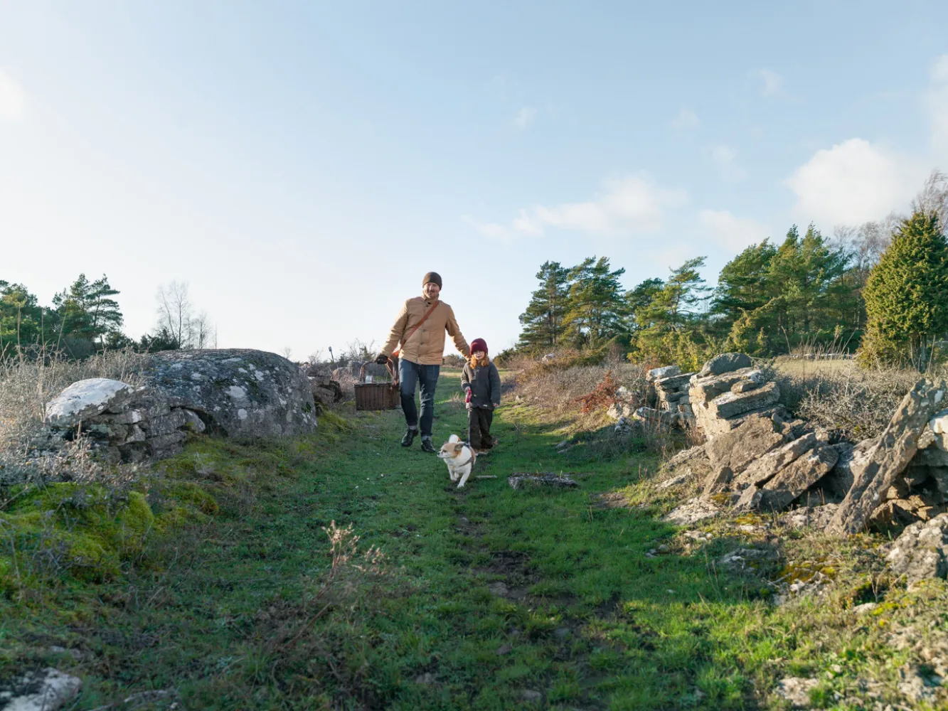 En pappa med sitt barn och hund går en promenad vid Penåsa Ödeby  på södra Öland.