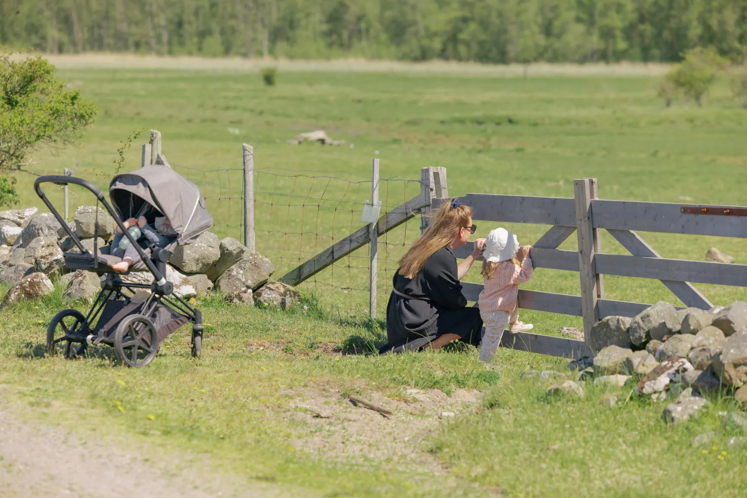 En kvinna och ett barn står och kollar ut i en hage