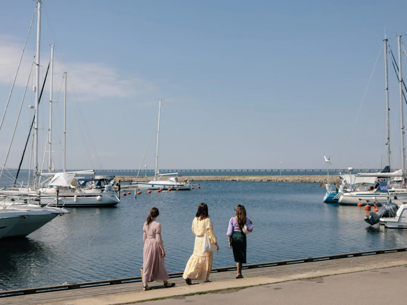 Tre kvinnor promenerar vid färjestadens hamn
