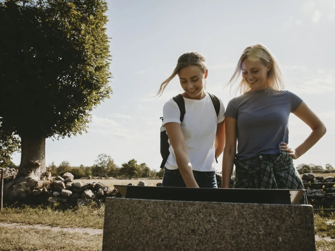 två tjejer står och läser på en informationstavla vid Mittlandsleden på Öland. 