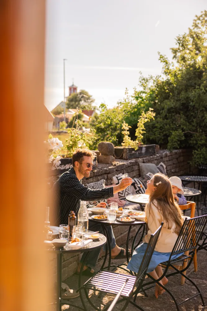 Familj sitter och äter middag utomhus 