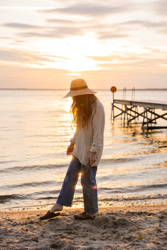 En kvinna står på stranden in solnedgången