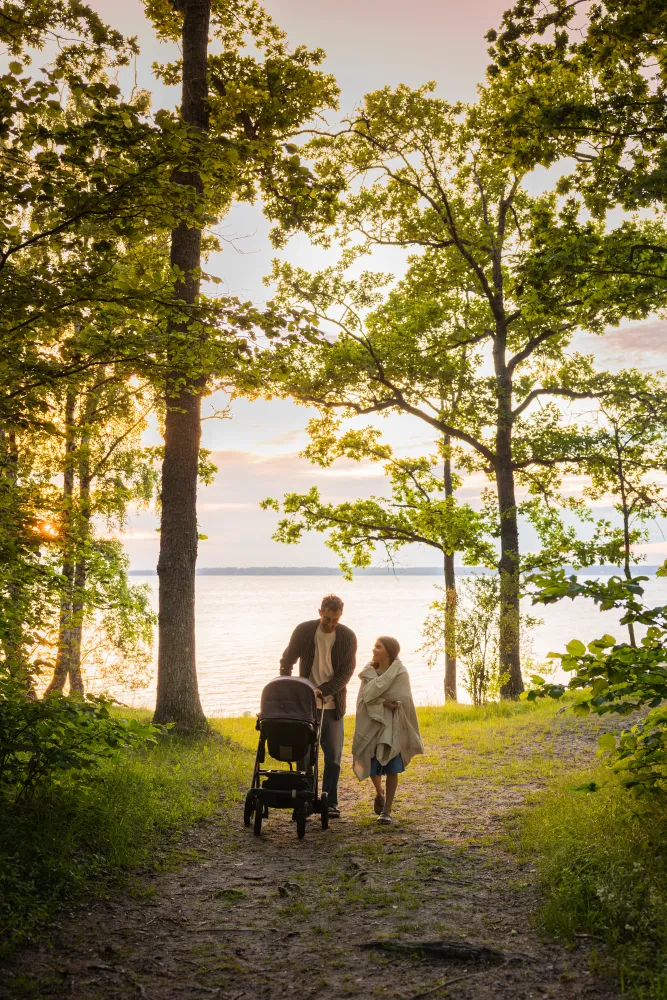 Familj går upp från stranden med en barnvagn genom naturen