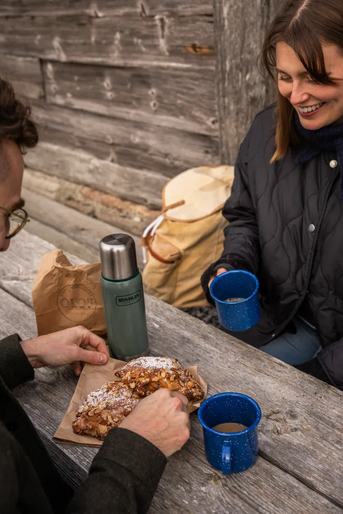 Två personer fikar på kaffe och bulle utomhus