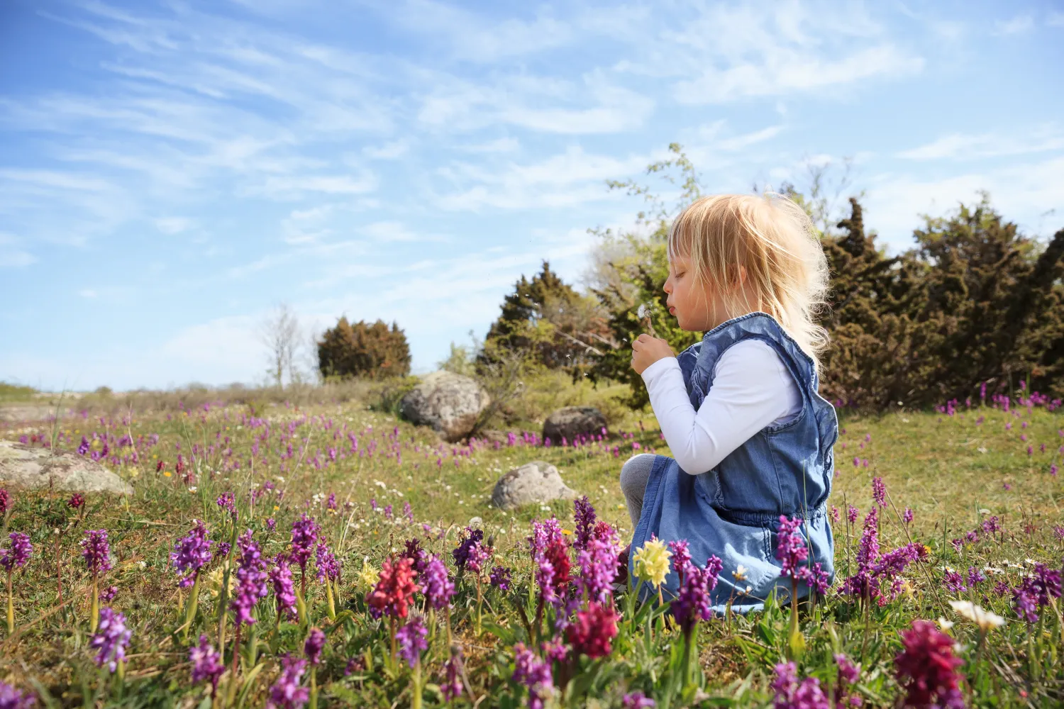 Ett barn sitter bland orkidéer