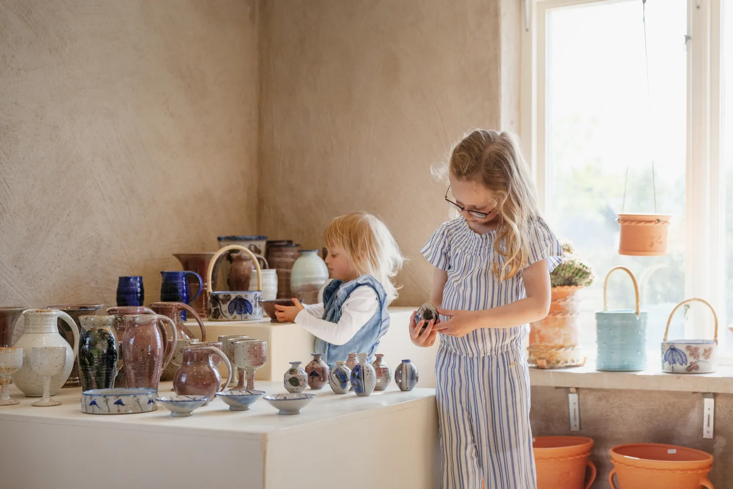 Två barn tittar på keramikföremål i en butik.