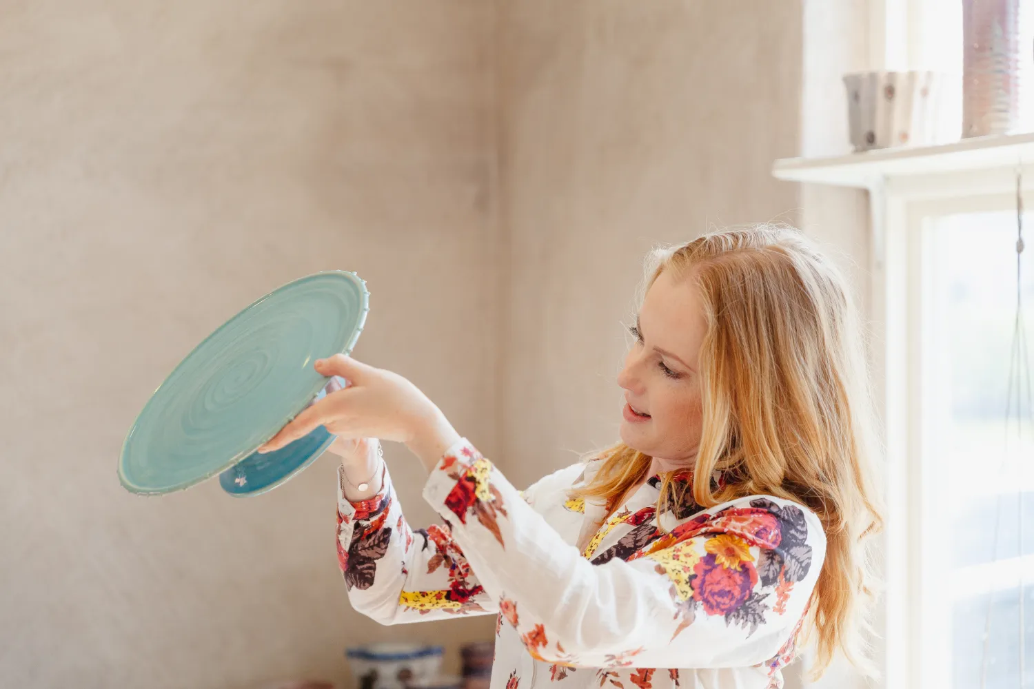 En kvinna stor och kollar på ett tårtfat i krukmakeriet