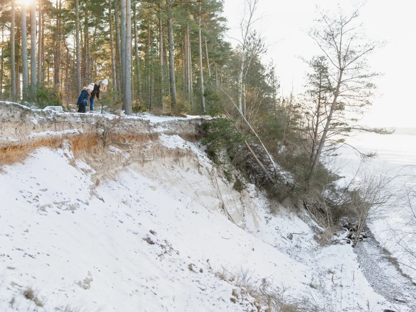 Vinterutflykt till Sandbergen på Öland. Mamma och dotter kikar över den höga strandkanten. 