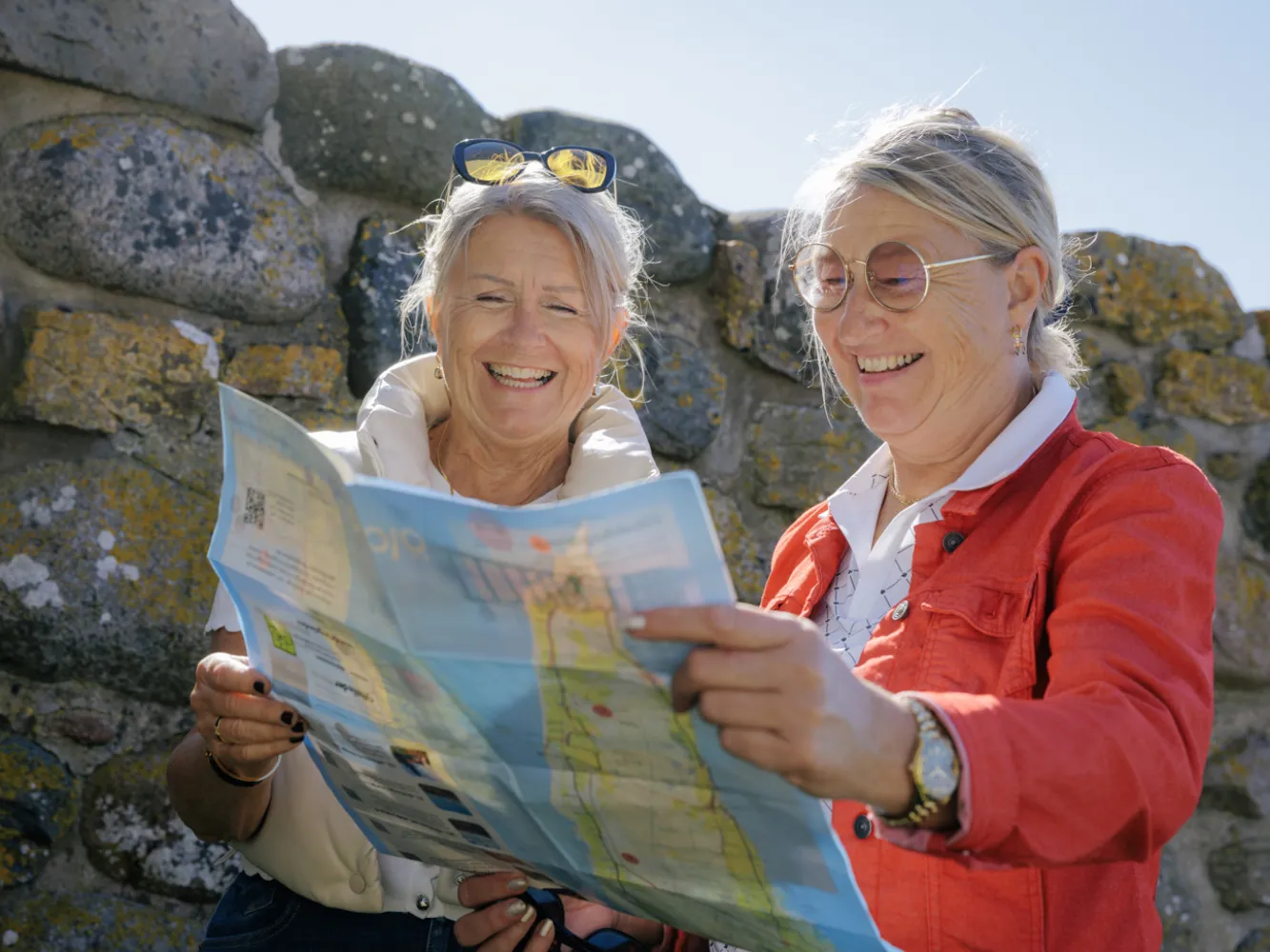 Två kvinnor kollar på en turistkarta och ser glada ut. 