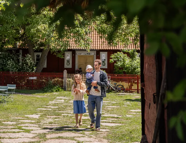 Familj promenerar genom en kringsbyggd ölandsgård