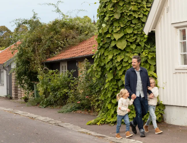 Bland pitorerska hus i Mörbylånga köping går en pappa med sina små barn i varsin hand.
