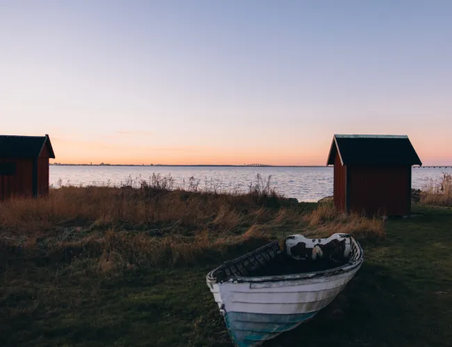 Sjöbodar och en vit båt uppdragen på land i Färjestaden på Öland