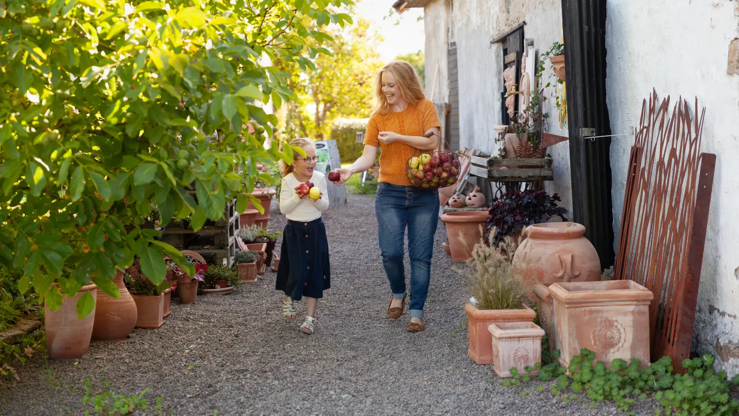 Barn och vuxen bär skörd i famnen