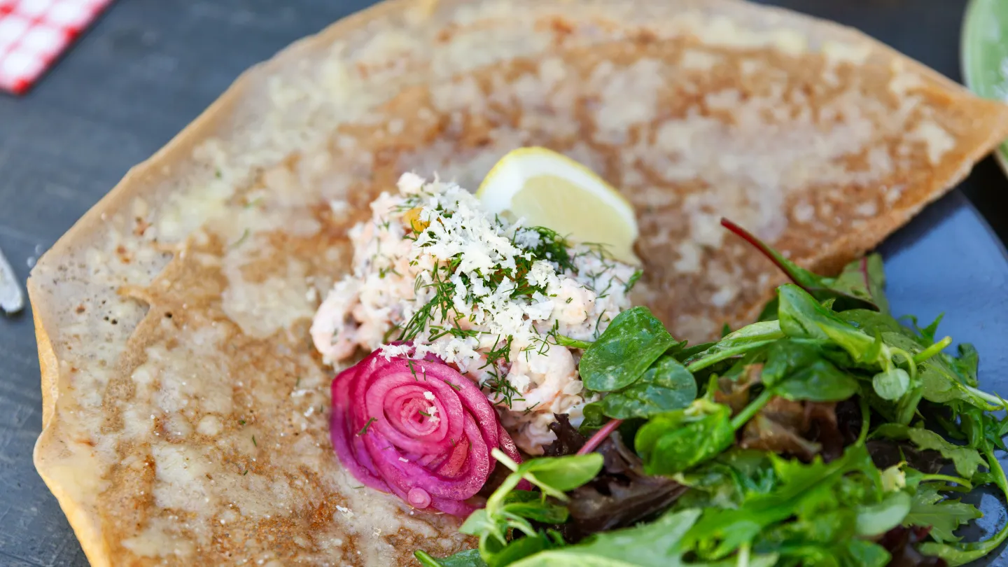 En crepe med fyllning och sallad ligger på en tallrik.
