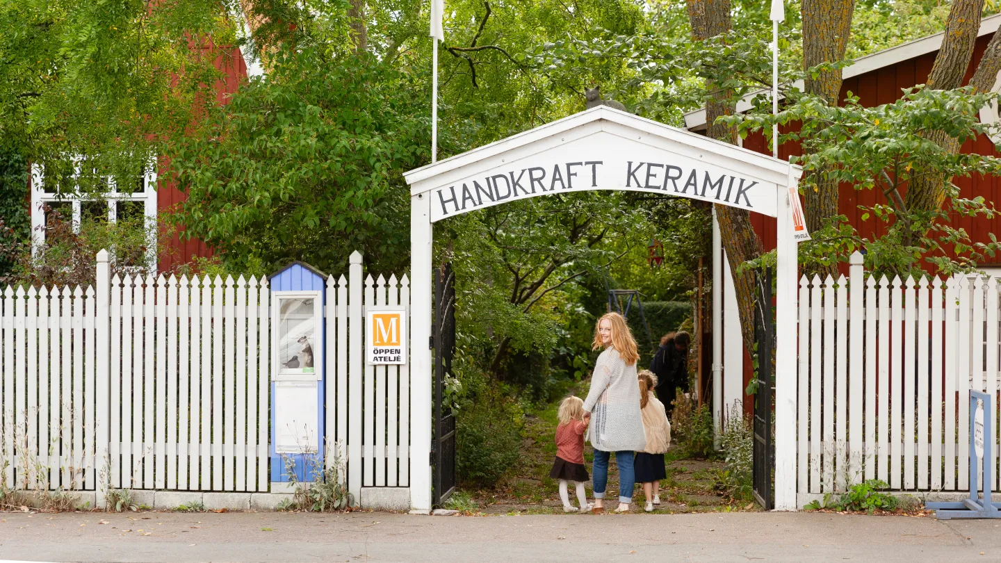 En kvinna och två barn går genom en grind till ett hantverksområde.