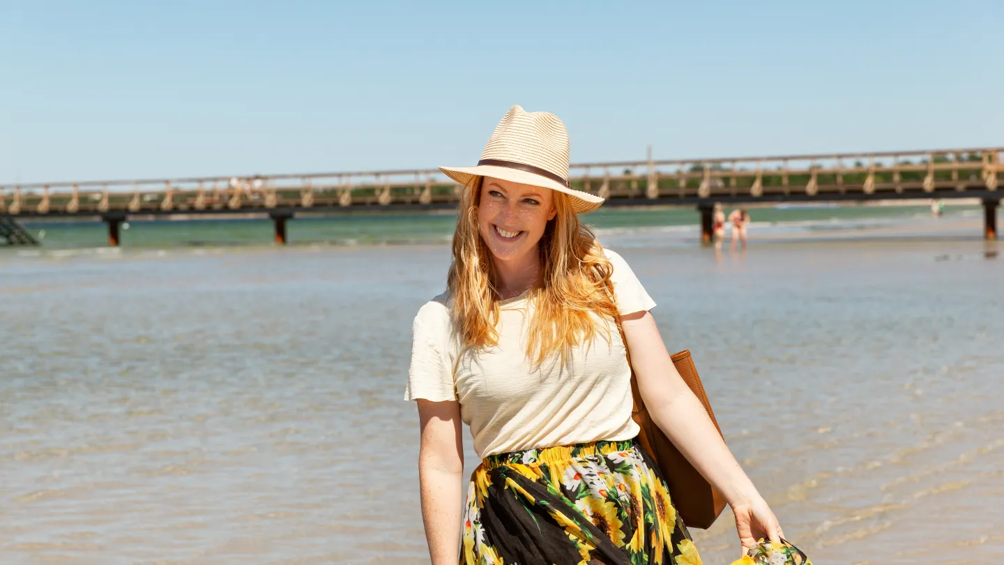 En kvinna står vid stranden och ler.