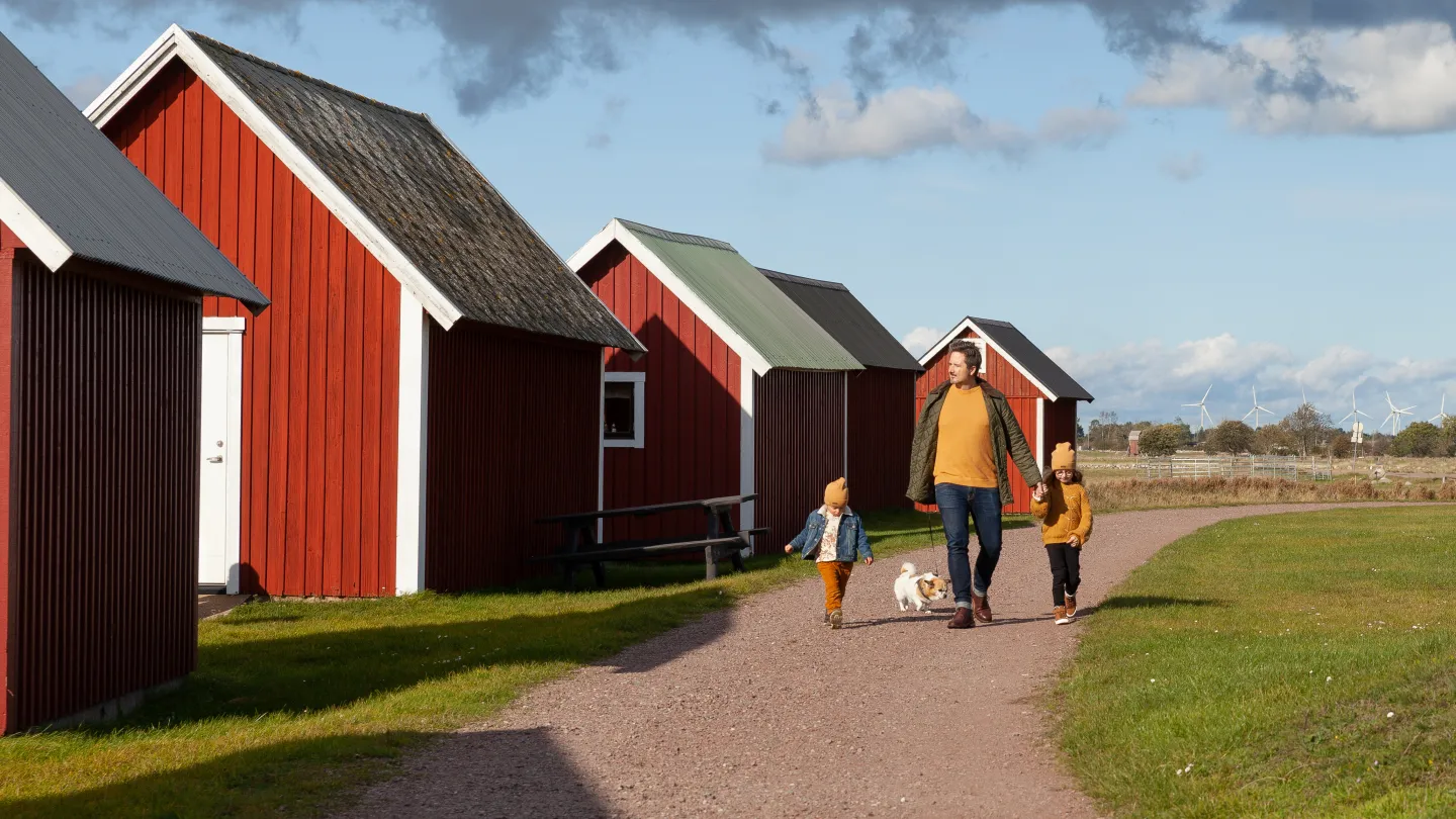 Familj som promenerar längs sjöbodar