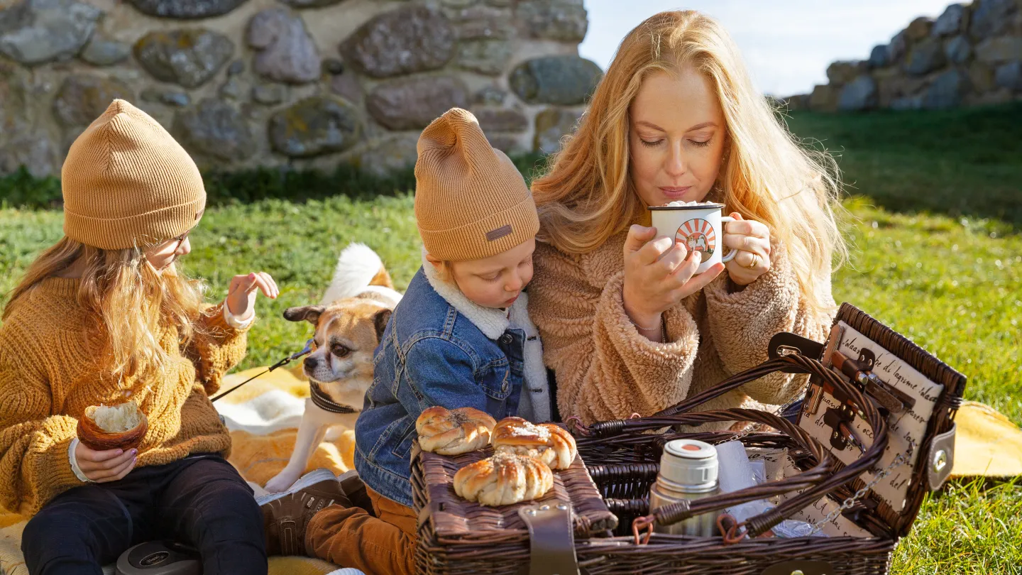 Familj som har picknick och äter bullar