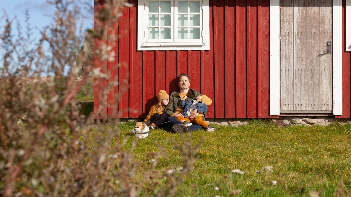 En familj som sitter framför en sjöbod