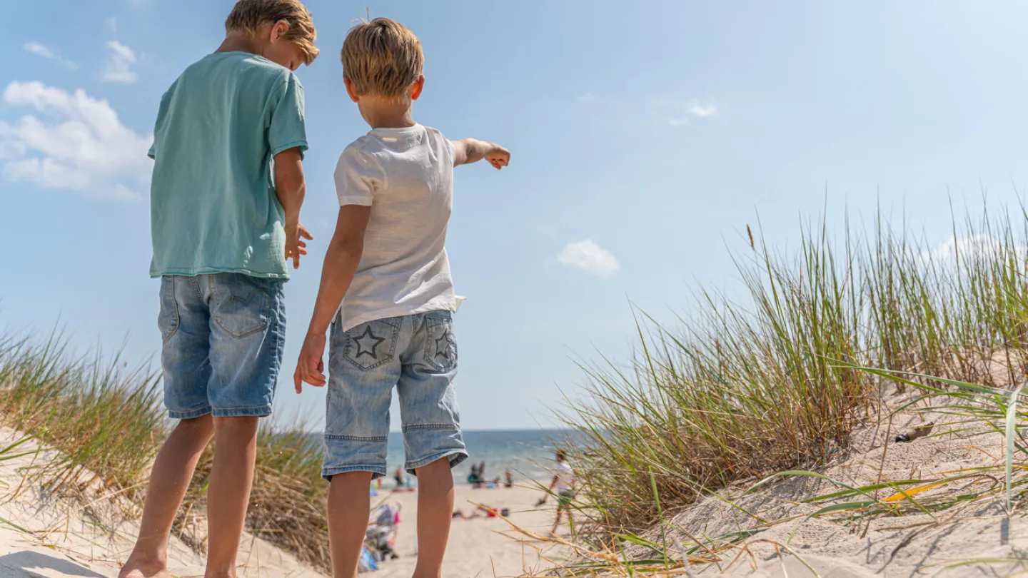 Två små killar pekar ut mot vattnet vid Bödabukten på Öland