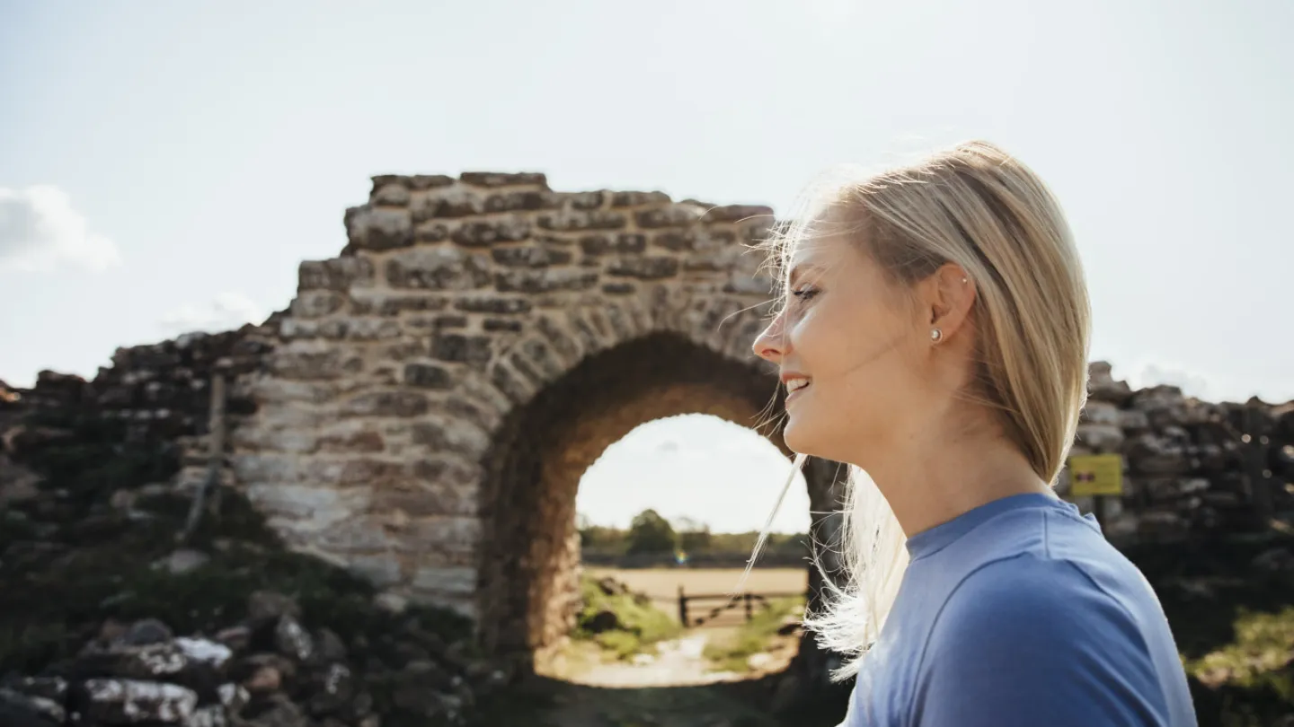 Une jeune fille se tient devant le portail de Gråborg, sur l'île d'Öland.