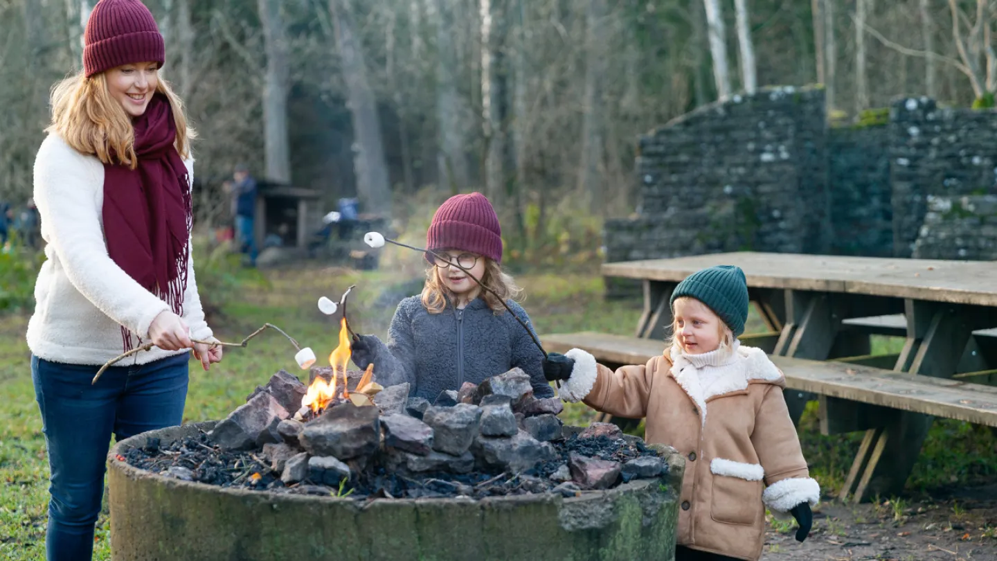 En mamma med sina två små döttrar grillar marshmallow vid Penåsa grillplats på södra Öland.