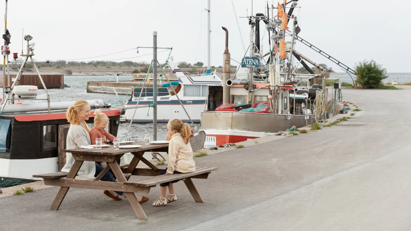 Familj sitter vid ett bord i en hamn