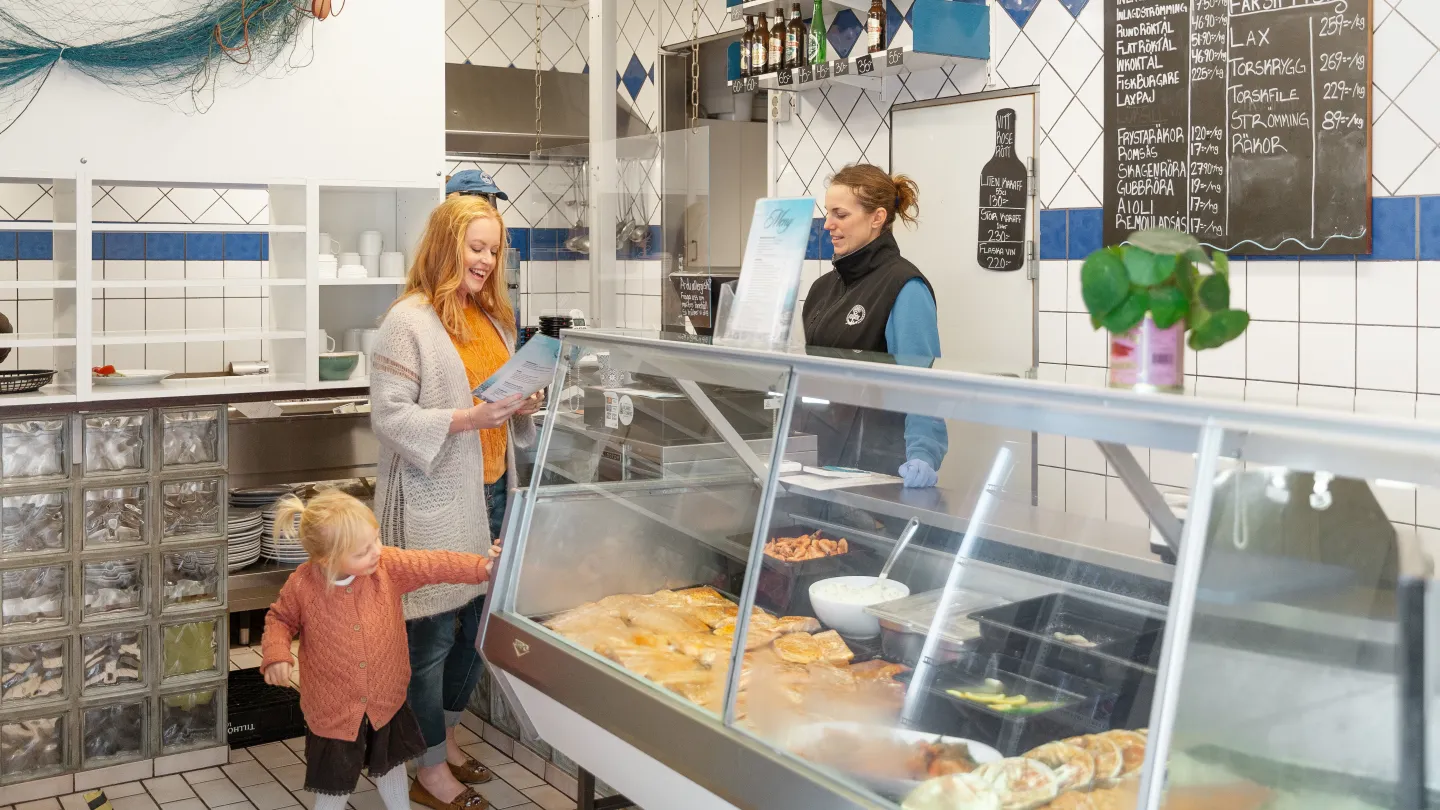 En kvinna och ett barn beställer fisk i en butik.