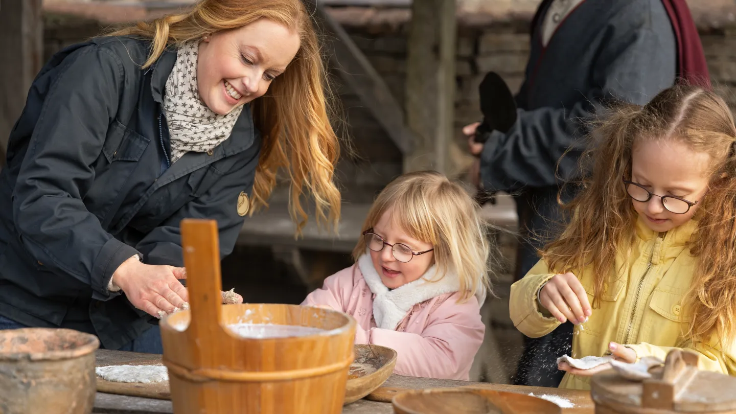 Barn och vuxen bakar bröd tillsammans utomhus.