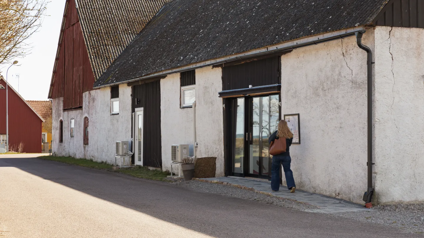 Person går in i lantlig byggnad.