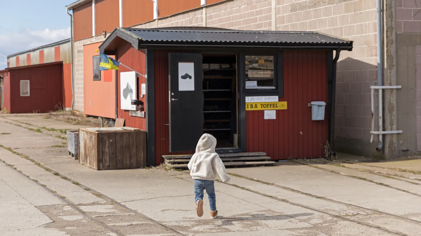 Barn springer mot en röd liten toffelbod.