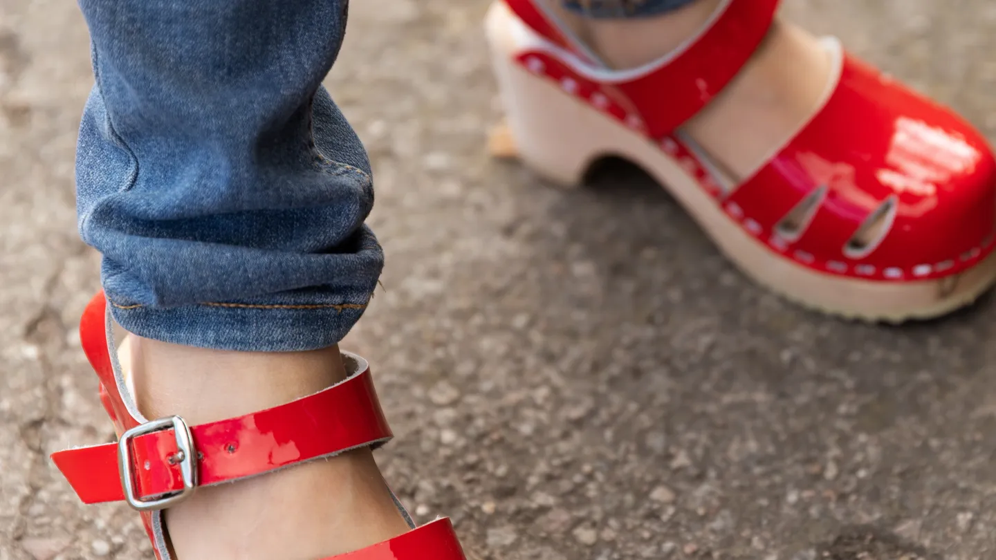 Ett barn har på sig att par röda träskor
