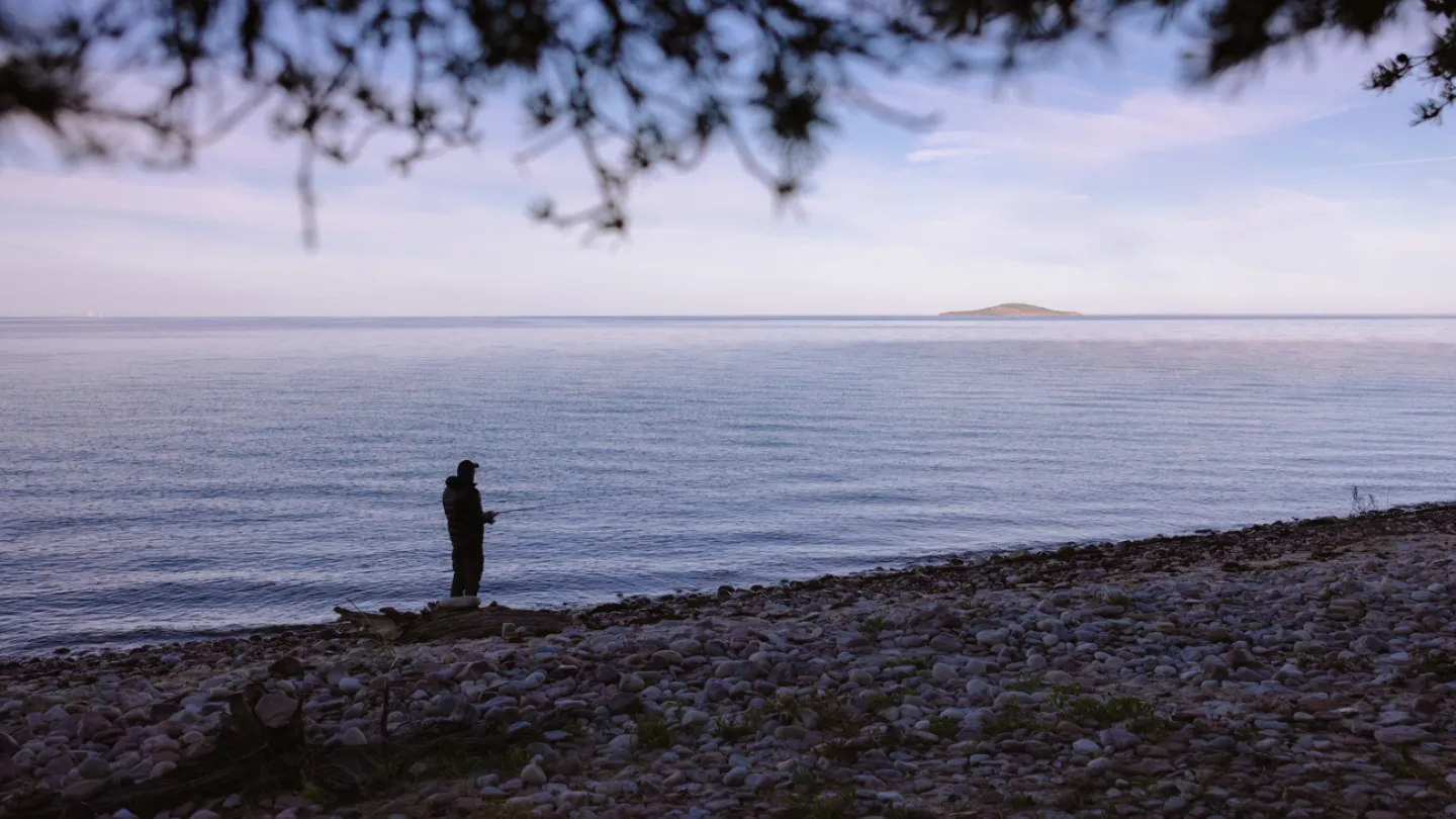 En man som fiskar på Öland med utsikt mot Blå Jungfrun
